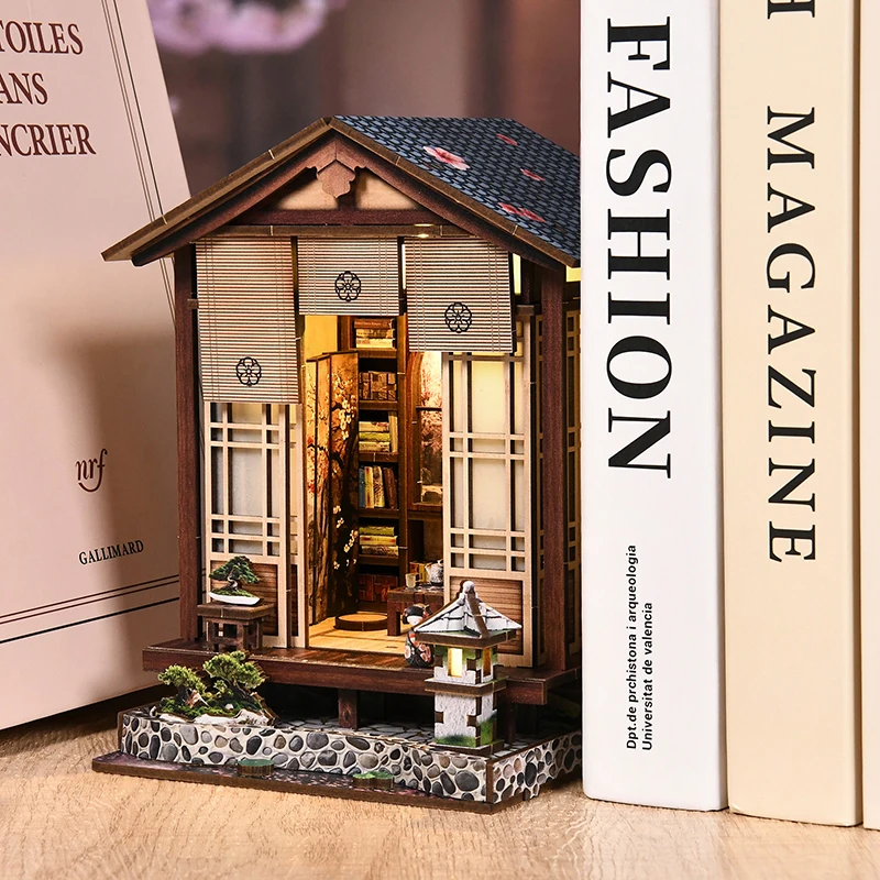 The Moss Garden Veranda book nook glowing on a shelf between books